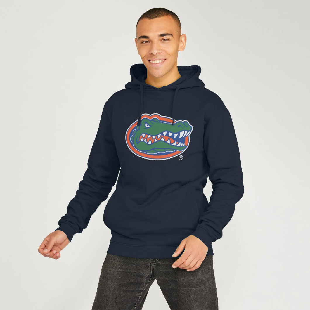 A man wearing a navy blue hoodie with a Florida Gators alligator logo on the chest, paired with dark gray jeans, standing against a light gray studio background.