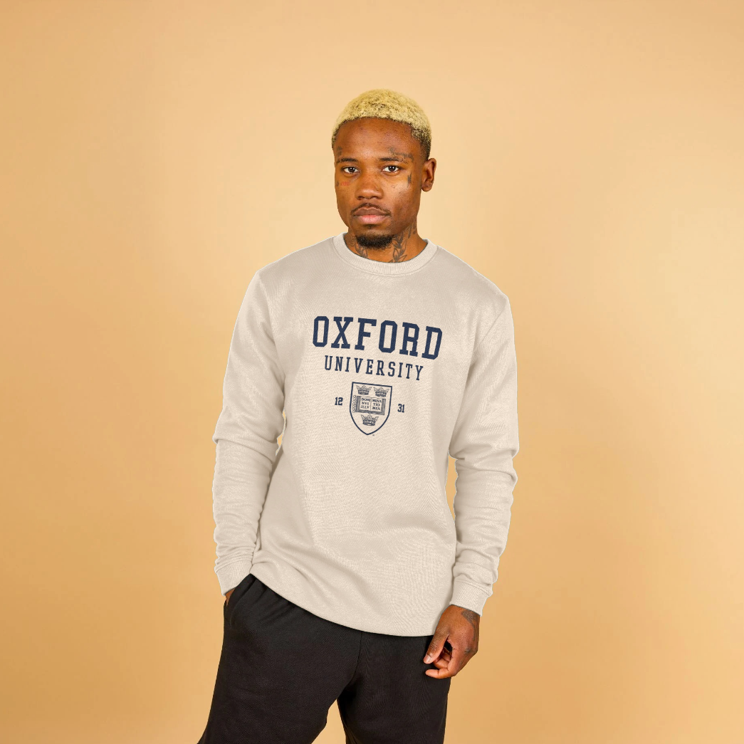Man wearing an Oxford University sweatshirt against a beige background