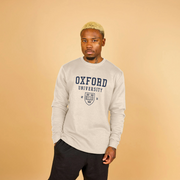 Man wearing an Oxford University sweatshirt against a beige background