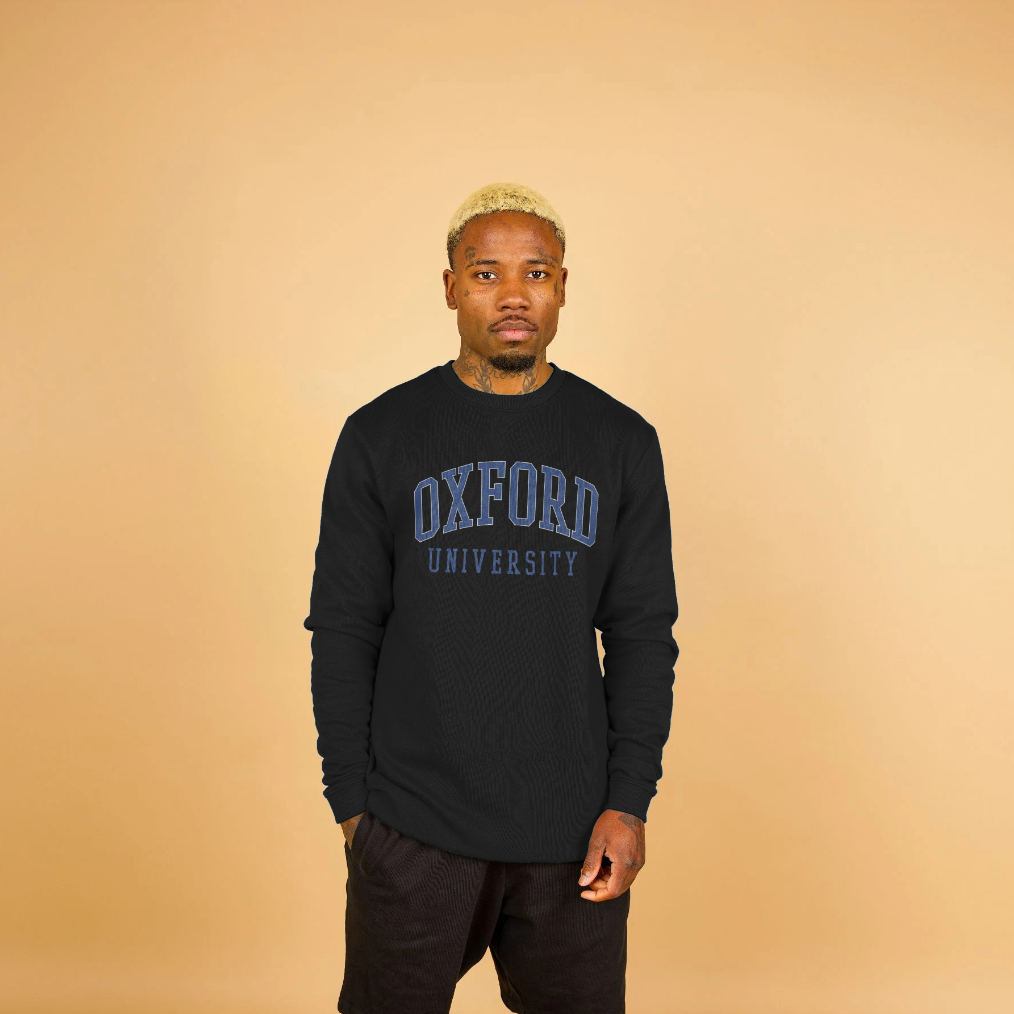 Person wearing a black 'Oxford University' sweatshirt against a beige background