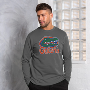 A man wearing a dark gray long-sleeve shirt with a Florida Gators alligator head and 'Gators' logo on the chest, standing indoors near a glass block window.