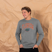 A man wearing a heather gray long-sleeve sweatshirt with 'FLORIDA' in orange varsity letters and the Florida Gators logo on the front, posed against a crumpled brown paper backdrop.