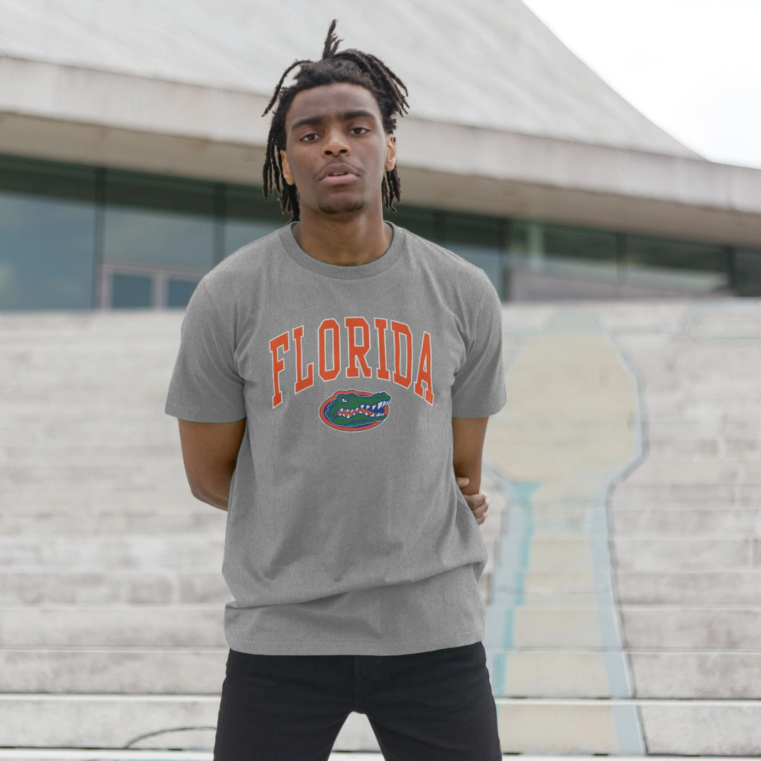 A man wearing a heather gray t-shirt with 'FLORIDA' and the Florida Gators logo printed on the front, standing on outdoor concrete steps.